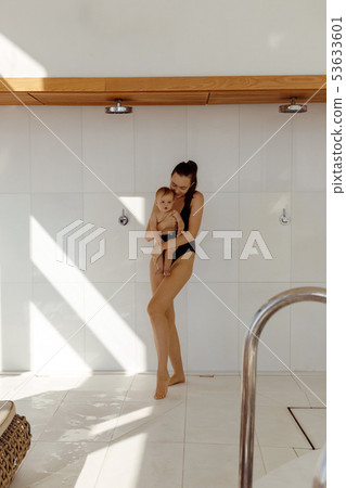 Mom in swimsuit with baby in shower Mom in swimsuit with baby in shower 53633601