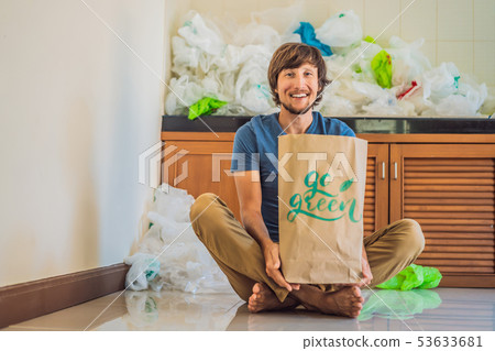 Man holding a package with the inscription GO GREEN amid a pile of plastic bags. Zero waste concept 53633681