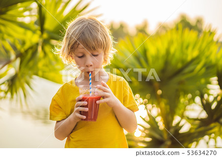 Boy drink healthy smoothies against the backdrop of palm trees. Watermelon smoothies. Healthy 53634270