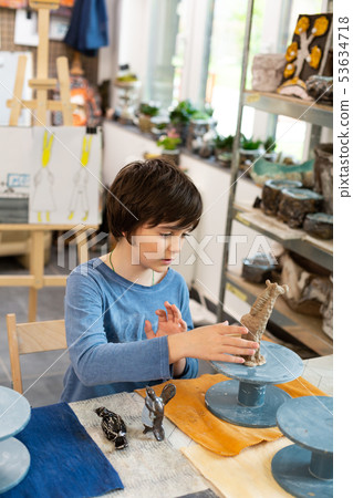 Talented schoolboy sculpting clay figures in art school 53634718