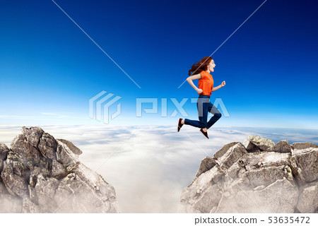 Redhead woman jumps through the gap between hills. 53635472