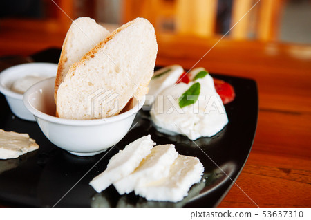 Baguette bread and fresh cheese in black plate 53637310
