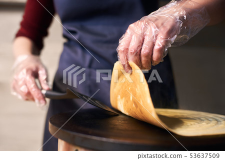Chef hands turn over crepe with spatula helping on portable cooktop. Baking process. Blurred Chef hands turn over crepe with spatula helping on portable cooktop. Baking process. Blurred 53637509