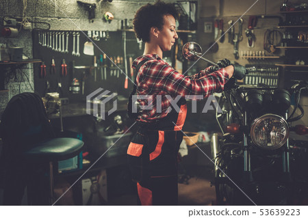 African american woman mechanic repairing a motorcycle in a workshop 53639223