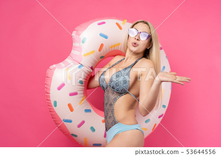 Image of girl in swimsuit sunglasses with inflatable donut for swimming on empty pink background 53644556
