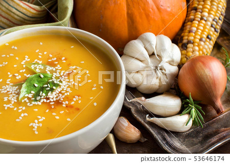 Fresh pumpkin soup with a spoon and vegetables Fresh pumpkin soup with a spoon and vegetables 53646174