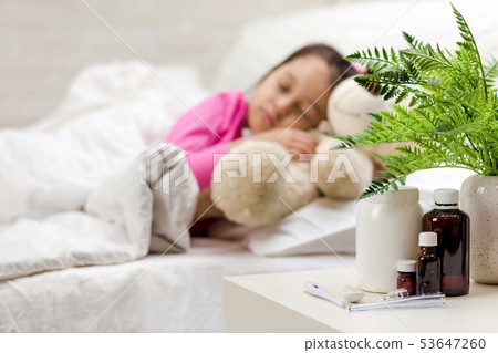 Sick little girl lying in bed with thermometer Sick little girl lying in bed with thermometer 53647260