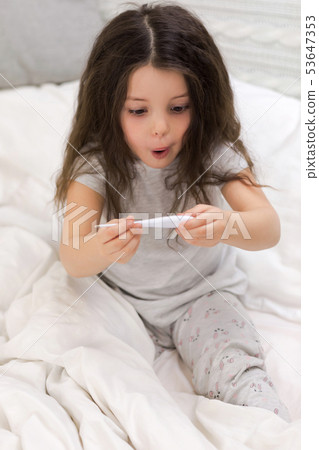 Sick little girl lying in bed with thermometer Sick little girl lying in bed with thermometer 53647353
