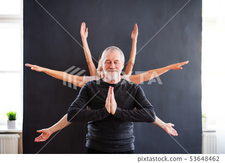 Senior man with multiple arms doing yoga exercise in community center club. 53648462
