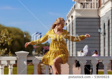 Beautiful blonde in a yellow dress on a Sunny day 53649828