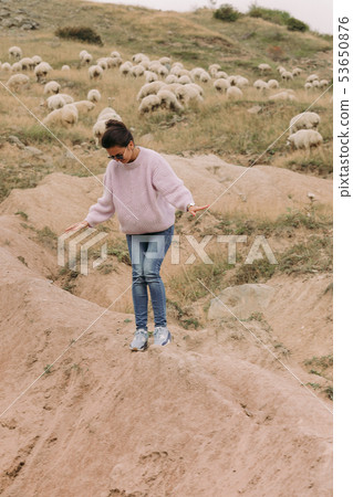 Happy young woman against herds of sheep in the mountains 53650876