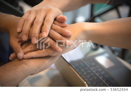 Business people join hands over laptop in office. 53652934