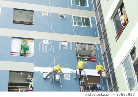 painters hang on roll, painting color on building. 53652938