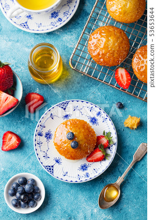 Muffin, cupcake with fresh berries on a plate. Blue background. Top view. Muffin, cupcake with fresh berries on a plate. Blue background. Top view. 53653644
