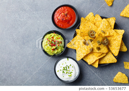 Nachos chips on a plate with sauces, dip variety. Grey stone background. Top view. Copy space. Nachos chips on a plate with sauces, dip variety. Grey stone background. Top view. Copy space. 53653677