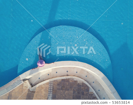 Young woman sunbathing in a swimming pool 53653814