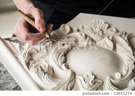 Hands of the sculptor with the tool. The sculptor works in the Studio. Creation of a decorative Hands of the sculptor with the tool. The sculptor works in the Studio. Creation of a decorative 53655274