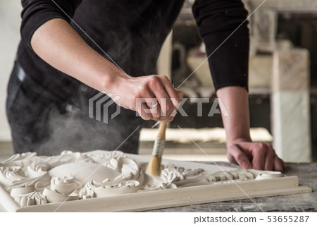Hands of the sculptor with the tool. The sculptor works in the Studio. Creation of a decorative Hands of the sculptor with the tool. The sculptor works in the Studio. Creation of a decorative 53655287