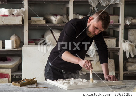 The sculptor works in the Studio. Creation of a decorative element from plaster. Luxurious stucco in The sculptor works in the Studio. Creation of a decorative element from plaster. Luxurious stucco in 53655293