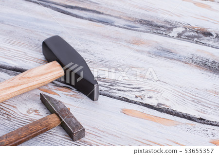 Two different hammers on wooden background. Two different hammers on wooden background. 53655357