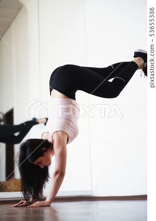 Young fit woman doing handstand exercise in gym 53655386