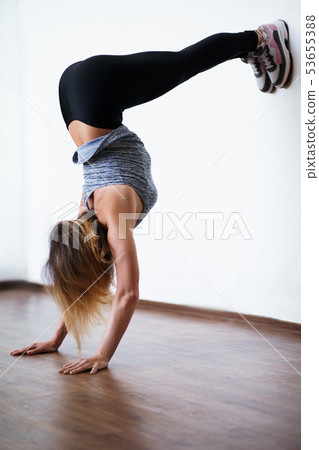 Young fit woman doing handstand exercise in gym 53655388