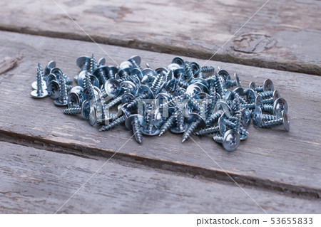 Heap of metal screws on wooden background close up. 53655833