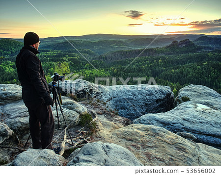 Photographer takes photos with camera on tripod on 53656002