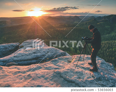 Photographer with tripod on cliff and thinking. 53656003