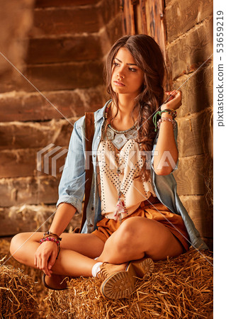 young cowboy girl sitting on a straw in a barn 53659219