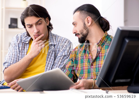 Two it specialists working in the office  53659619
