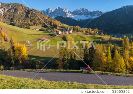 Tourist on bench looks at beautiful Dolomites Tourist on bench looks at beautiful Dolomites 53665862