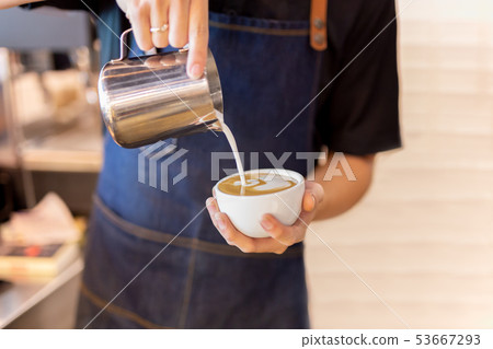 Barista hand pour milk making latte art coffee at cafe. Barista hand pour milk making latte art coffee at cafe. 53667293