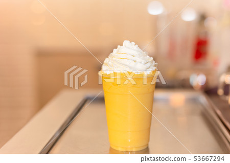 Fresh orange smoothie in plastic glass with cream on top. Fresh orange smoothie in plastic glass with cream on top. 53667294