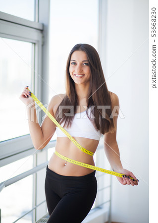 Diet. The girl taking measurements of her body, white background Diet. The girl taking measurements of her body, white background 53668230