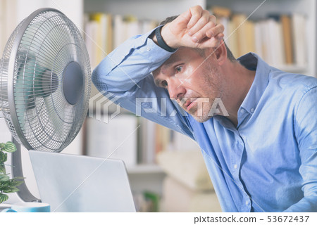 Man suffers from heat in the office or at home 53672437