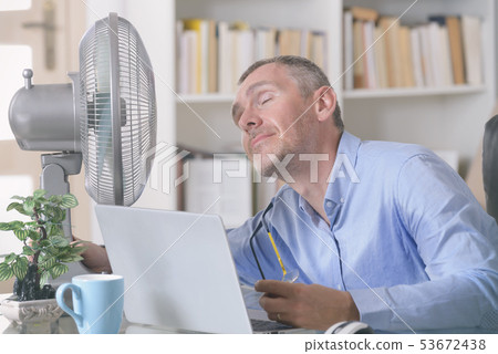 Man suffers from heat in the office or at home 53672438