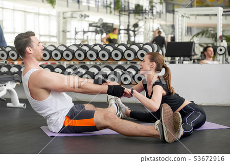 Young fit couple holding hands and stretching together. Young fit couple holding hands and stretching together. 53672916