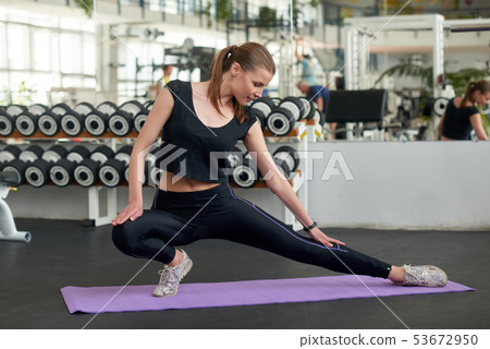 Young fit woman stretching leg at gym. 53672950