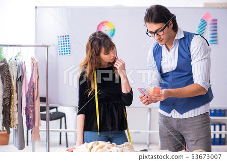 Young male tailor teaching female student  53673007