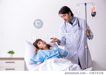 Male doctor visiting female patient in ward  53673236