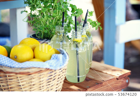Fresh lemonade and a basket with lemons on a woode Fresh lemonade and a basket with lemons on a woode 53674120