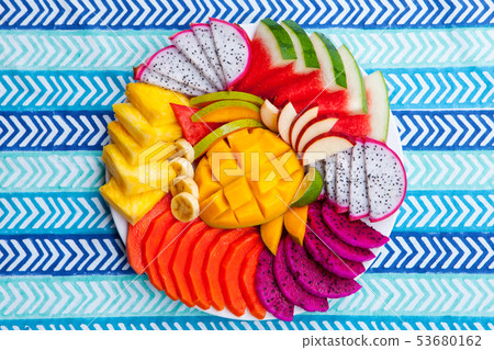 Tropical fruits assortment on a white plate, blue colorful textile background. Top view. Copy space. Tropical fruits assortment on a white plate, blue colorful textile background. Top view. Copy space. 53680162