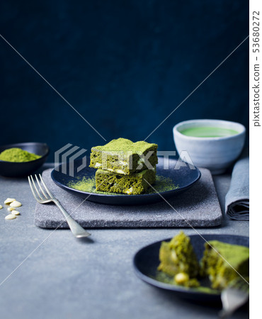 Matcha green tea cake, bars, brownie with white chocolate on a plate. Grey background. Copy space. Matcha green tea cake, bars, brownie with white chocolate on a plate. Grey background. Copy space. 53680272