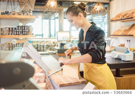 Shop clerk in deli cutting cheese 53683068