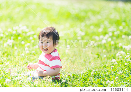 一個嬰兒坐在草地上帶著微笑(寶貝) 一個嬰兒坐在草地上帶著微笑(寶貝) 53685144