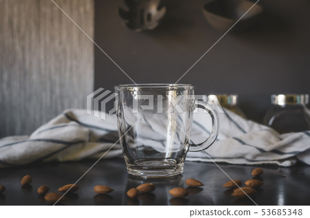 Glass empty mug. Around almonds, staged photo. 53685348