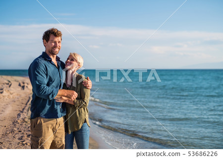 Young couple standing outdoors on beach, talking. Copy space. Young couple standing outdoors on beach, talking. Copy space. 53686226