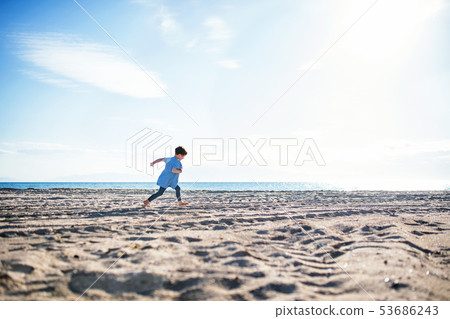 A small girl running outdoors on sand beach. Copy space. A small girl running outdoors on sand beach. Copy space. 53686243