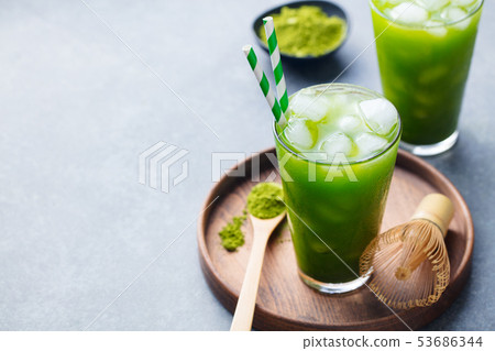 Matcha ice tea in tall glass on wooden plate. Grey stone background. Copy space. Matcha ice tea in tall glass on wooden plate. Grey stone background. Copy space. 53686344